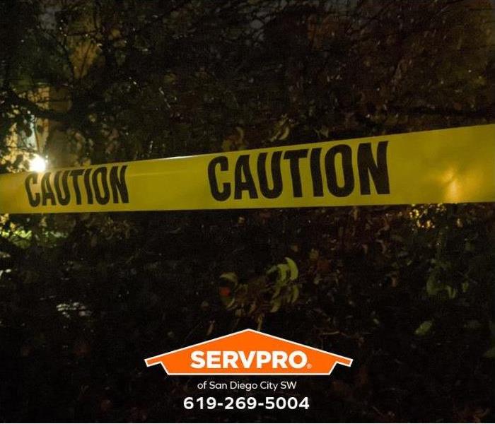 Yellow caution tape prevents entry into an area where a tree has fallen.