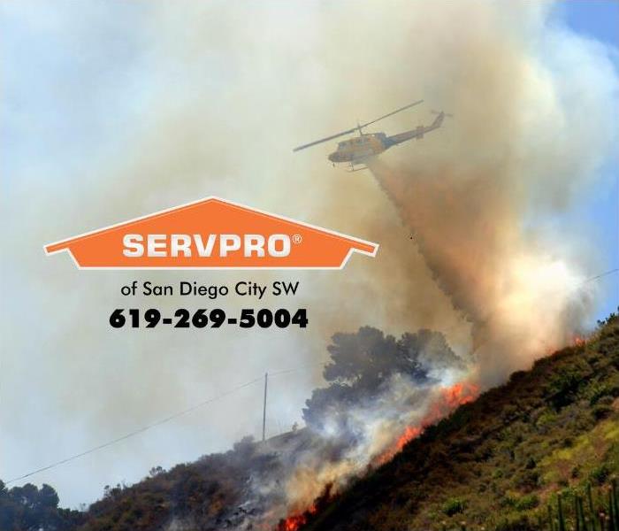 A fire fighting helicopter is shown dumping fire retardant onto a hillside wildfire in Southern California. 