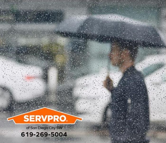 A man walks on a city street with an umbrella during a rainstorm.